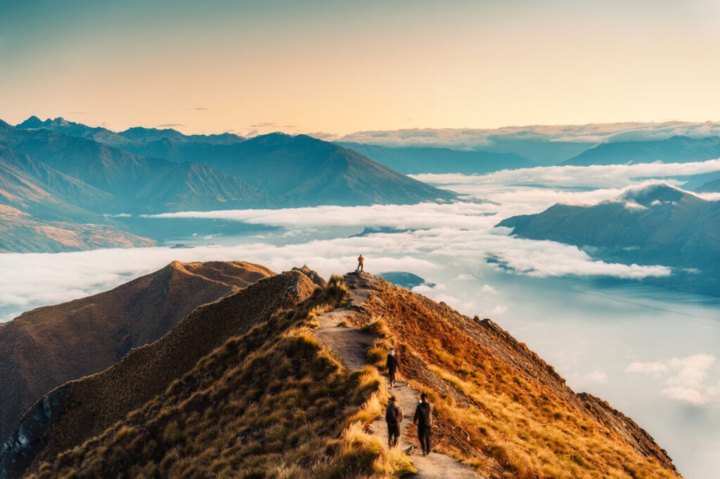 Abenteuer Reisen_ Mensch auf Berg und von Wolken umgeben