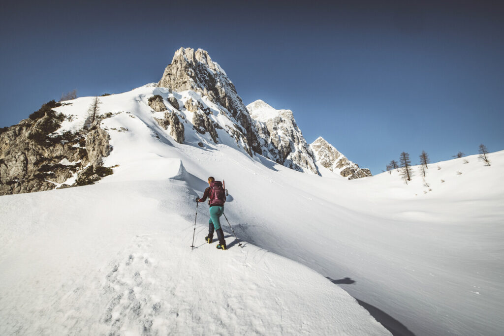 Frau, die mit Schneeschuhen wandert und auf Berge schaut