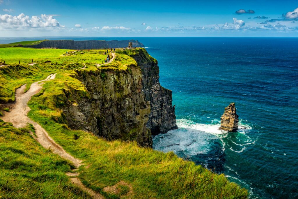 Die Cliffs of Moher in Irland ragen majestätisch über den Atlantik, mit steilen Felsen, grünen Wiesen und einem endlosen Blick aufs Meer.
