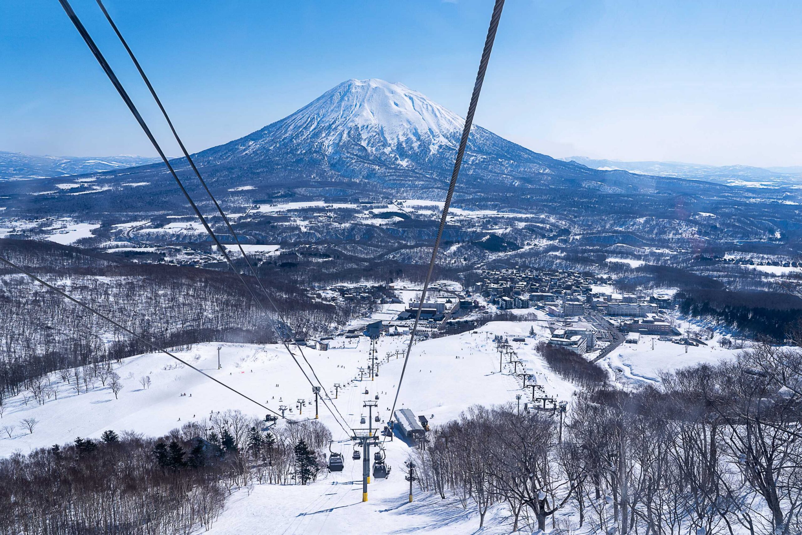 Japans Alpenregion bei Hokkaido - Mount Fuji im Hintergrund und im Vordergrund ein Skilift mit viel Schnee auf dem Berg