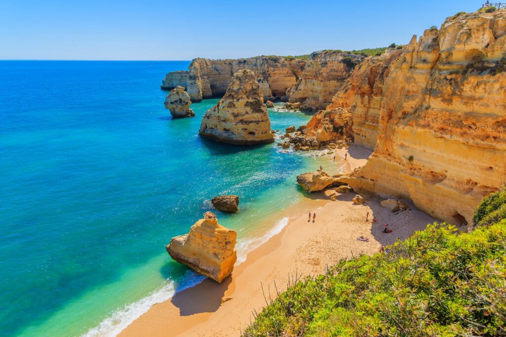 Panoramablick auf den Marinha-Strand an der Algarve in Portugal mit türkisblauem Wasser, goldenen Klippen und feinem Sandstrand.