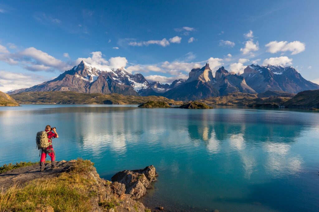 Person fotografiert den Nationalpark Torres del Paine mit seiner imposanten Gebirgskette am Lago Pehoe.