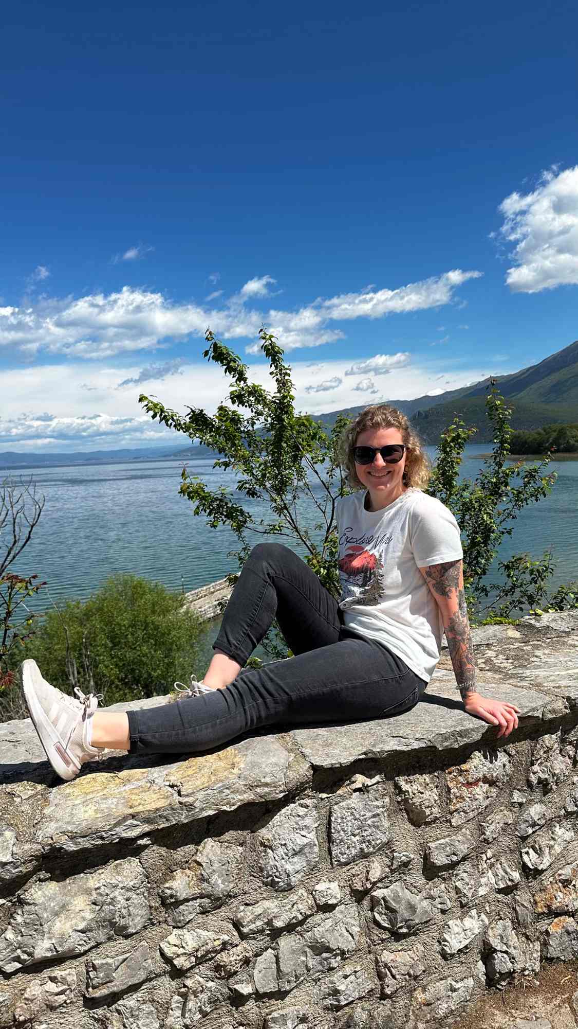 Nancy Schäfer in Albanien auf einer Mauer mit Meer im Hintergrund