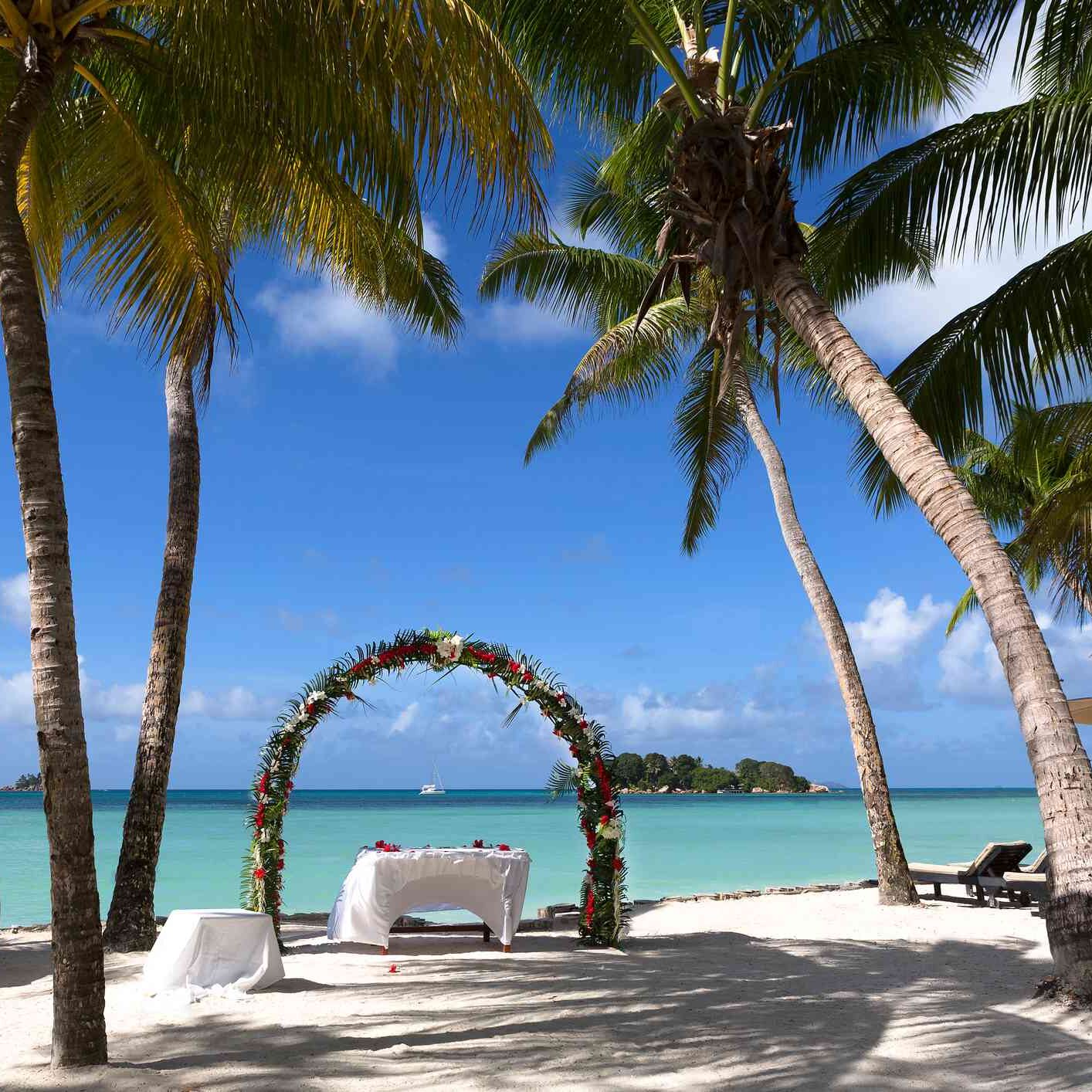 Altar für Hochzeit direkt am Strand mit Blumen und vielen Palmen