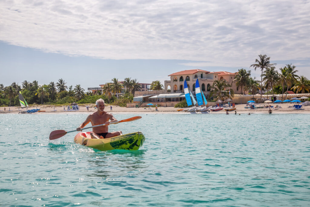 Elder fitter Mann fährt an einem sonnigen Sommertag Kajak auf einem leuchtend gelben Kajak in der Karibik. Aufgenommen in Varadero, Kuba.