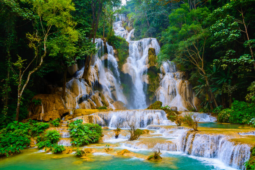 Mehrstufiger Wasserfall mit türkisfarbenen Naturpools, umgeben von dichtem, grünem Tropenwald.