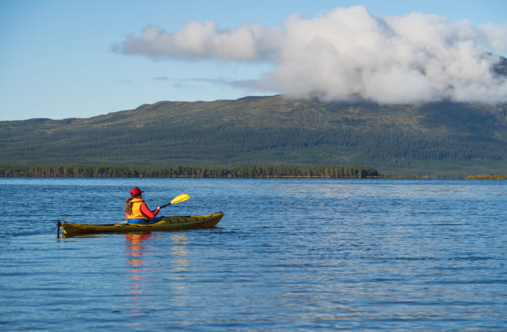Eine Frau fährt mit dem Kajak auf einem See in der Wildnis. Jämtland, Schweden.
