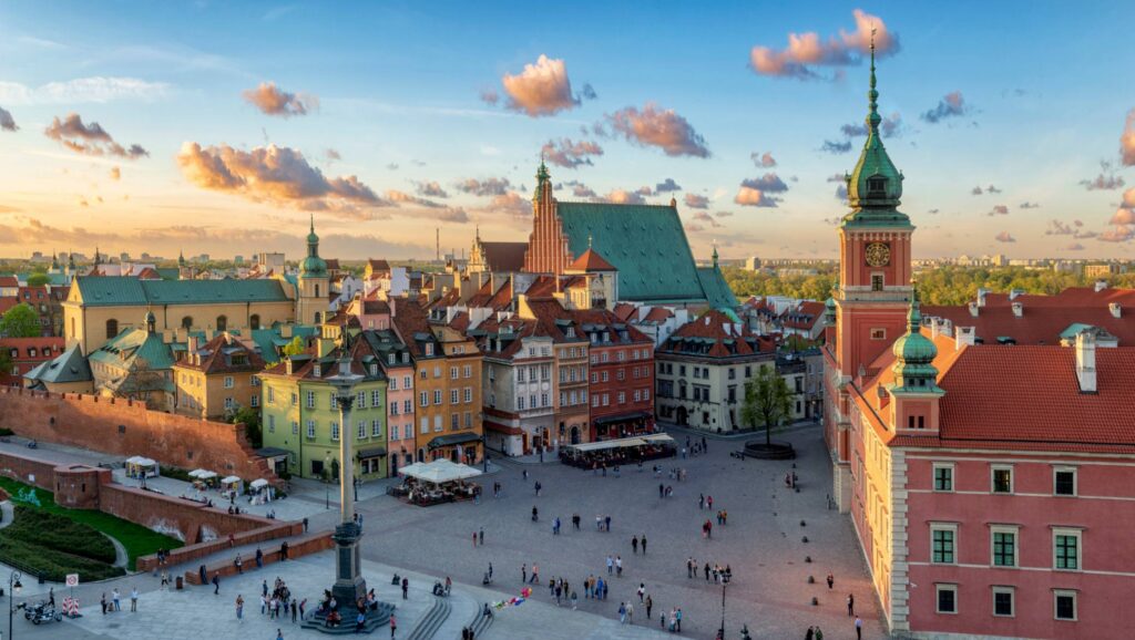 Panoramablick auf den Schlossplatz und die Altstadt von Warschau in Polen mit Königsschloss, Sigismundsäule und historischen Gebäuden bei Sonnenuntergang.