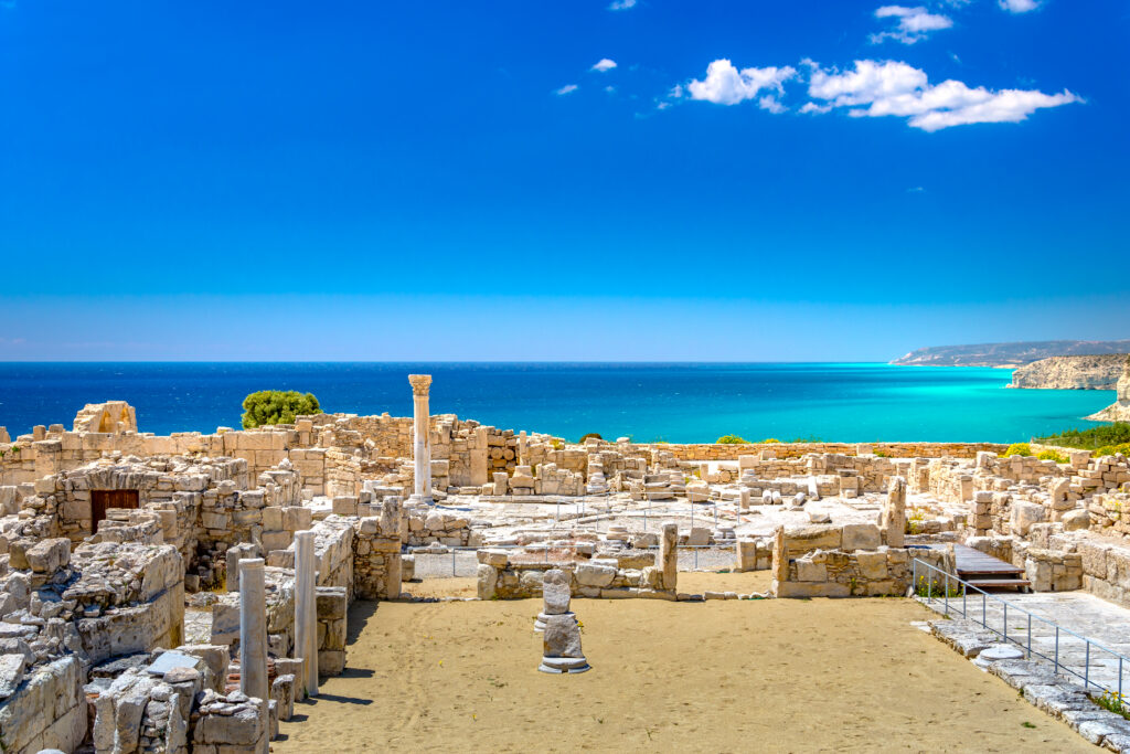 Ruinen der Kourion-Basilika und des Heiligtums von Apollo mit Säulenresten und Steinmauern, im Hintergrund das türkisfarbene Mittelmeer unter klarem Himmel auf Zypern.