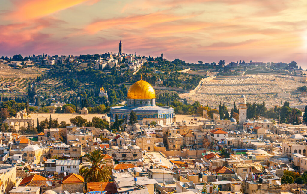 Blick auf Jerusalem mit dem goldenen Felsendom im Vordergrund und dicht bebauter Altstadt bei Sonnenuntergang.