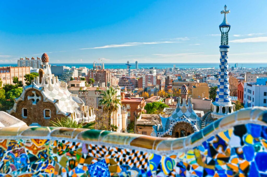 Bunte Mosaikgebäude im Park Güell in Barcelona, Spanien, mit Blick über die Stadt bis zum Meer.