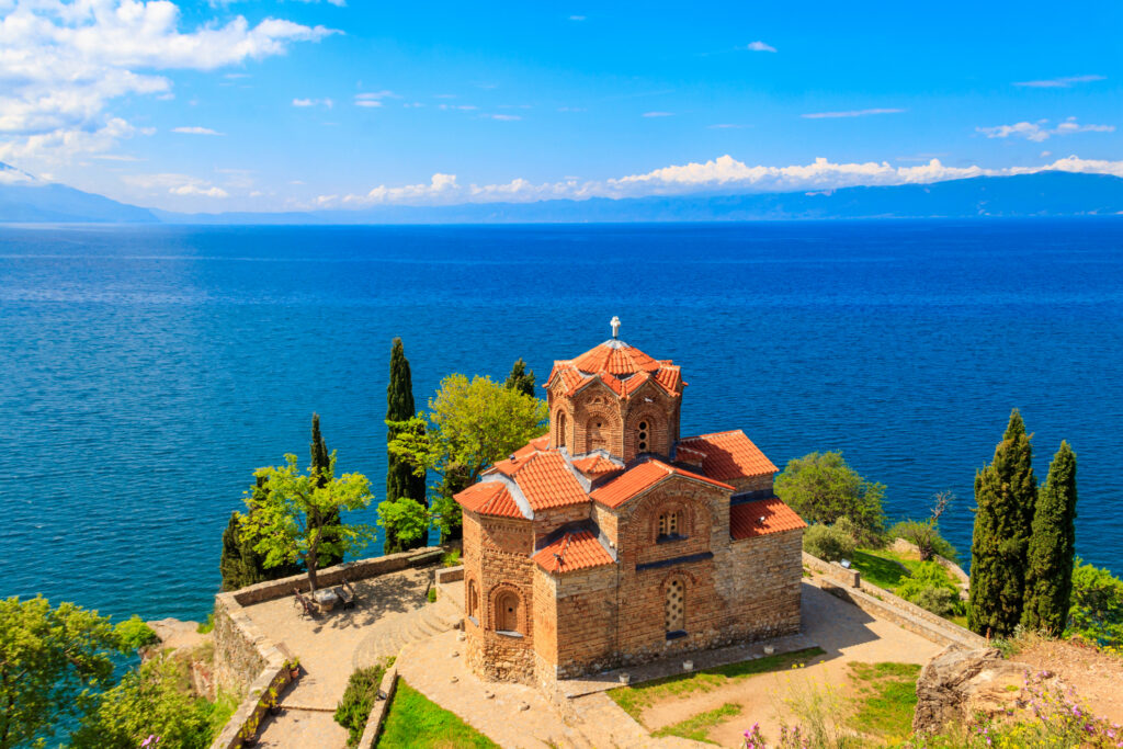 Kirche des Heiligen Johannes von Kaneo auf einer Klippe über dem Ohridsee in Ohrid, Nordmazedonien, mit blauem Himmel und klarem Wasser