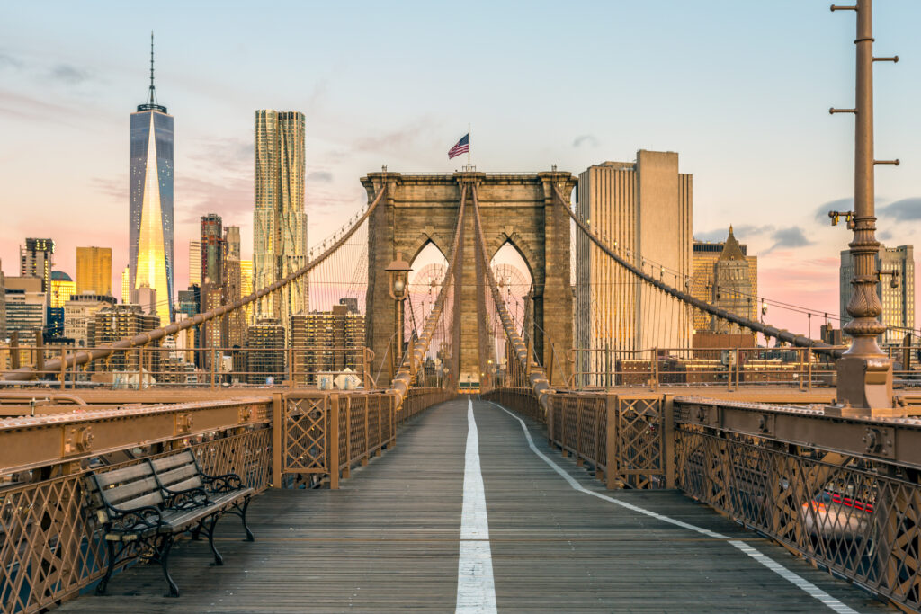 Die Brooklyn Bridge in New York City im sanften Morgenlicht, während die Sonne an einem klaren Herbsttag über Brooklyn aufgeht.