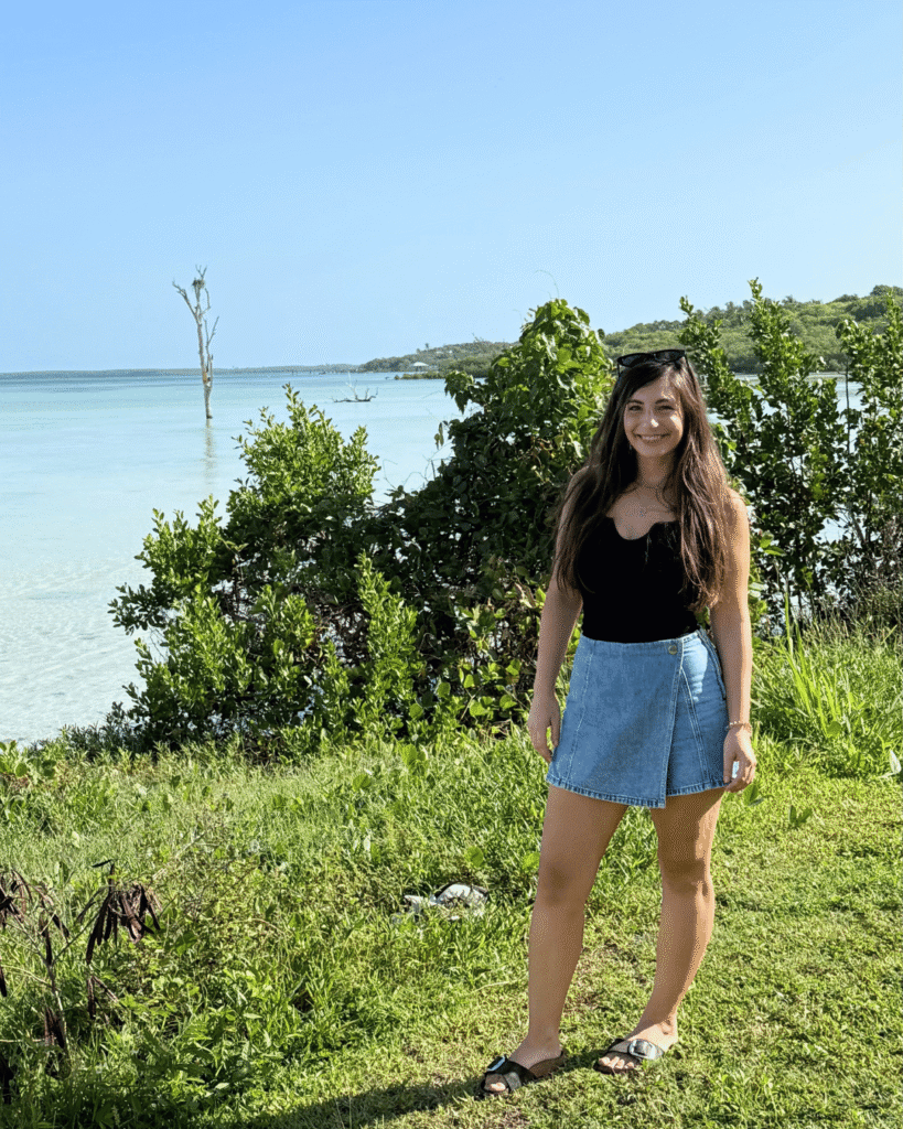 Frau steht im Grünen vor dem Meer