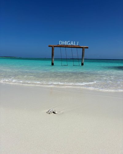 DHIGALI-Schaukel im flachen türkisfarbenen Wasser vor weißem Sandstrand und blauem Himmel auf den Malediven.