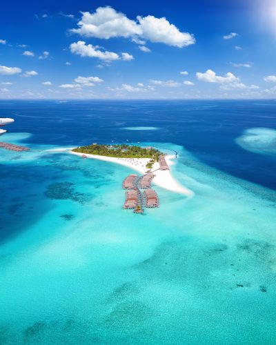 Luftaufnahme einer kleinen Malediven-Insel mit türkisfarbenem Wasser, Overwater-Bungalows und einem startenden Wasserflugzeug